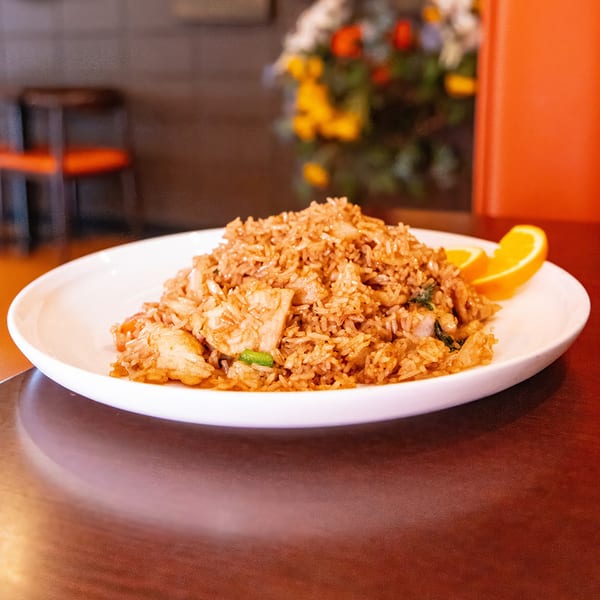 A large serving of Spice Club's chicken fried rice with orange slices on a white plate.